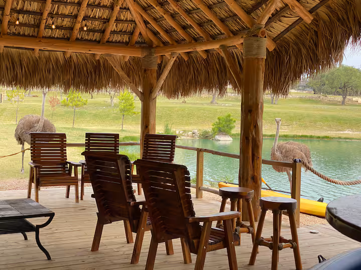 Wooden chairs and tables beneath the ranch's thatched gazebo