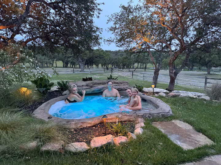 Guests relaxing in the illuminated rock-lined outdoor hot tub