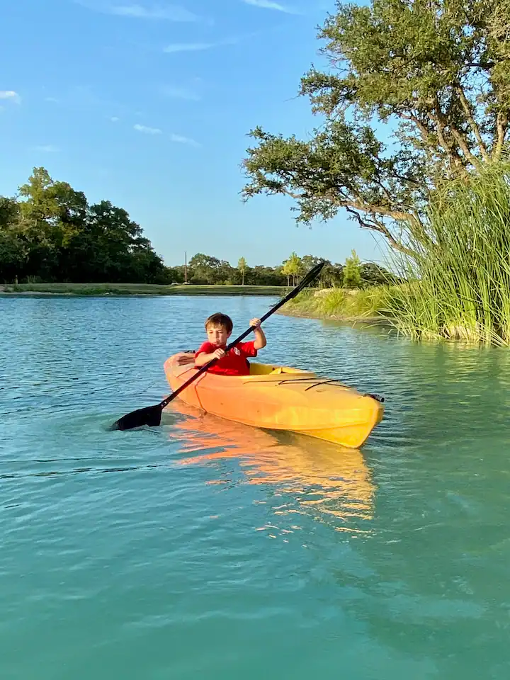 A guest paddling a yellow kayak on the ranch pond